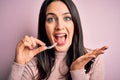 Young woman with blue eyes holding clear aligner standing over pink background very happy and excited, winner expression Royalty Free Stock Photo