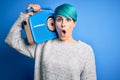 Young woman with blue fashion hair listening to music holding vintage portable radio scared in shock with a surprise face, afraid Royalty Free Stock Photo