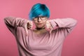 Young woman with blue hair on pink showing thumb down gesture of dislike Royalty Free Stock Photo