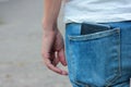 A young woman in blue jeans with a smartphone in her back pocket. Close-up of a black cell phone in the pocket. Royalty Free Stock Photo