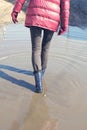 Young woman in blue rubber boots walking on a puddle. The concept of bad roads and floods. Melting snow in spring. Royalty Free Stock Photo