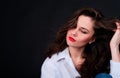 Young woman in blue shirt with weaving long hair and semiclosed