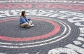 Young woman in blue sweatshirt alone sitting on street cobbled square and dreamily looking away Royalty Free Stock Photo