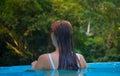 Young woman in blue swimming pool. Girl back in open swimming pool