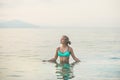 Young woman in blue swimsuit standing in still sea waters