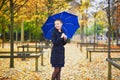 Young woman with blue umbrella in the Luxembourg garden of Paris on a fall or spring rainy day Royalty Free Stock Photo