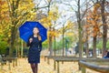 Young woman with blue umbrella in the Luxembourg garden of Paris on a fall or spring rainy day Royalty Free Stock Photo