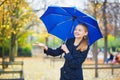 Young woman with blue umbrella in the Luxembourg garden of Paris on a fall or spring rainy day Royalty Free Stock Photo