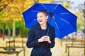 Young woman with blue umbrella in the Luxembourg garden of Paris on a fall or spring rainy day Royalty Free Stock Photo