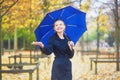Young woman with blue umbrella in the Luxembourg garden of Paris on a fall or spring rainy day Royalty Free Stock Photo