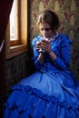 Young woman in blue vintage dress drinking tea in coupe of retro