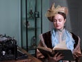 Young woman in blue vintage dress late 19th century reading the book in retro room Royalty Free Stock Photo