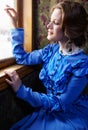 Young woman in blue vintage dress looking out the window in coup Royalty Free Stock Photo