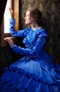 Young woman in blue vintage dress looking out the window in coup Royalty Free Stock Photo