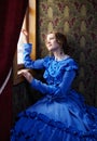 Young woman in blue vintage dress looking out the window in coup Royalty Free Stock Photo