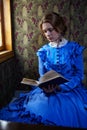 Young woman in blue vintage dress reading the book in coupe of r Royalty Free Stock Photo