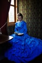 Young woman in blue vintage dress reading the book in coupe of r Royalty Free Stock Photo