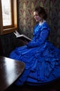 Young woman in blue vintage dress reading the book in coupe of r Royalty Free Stock Photo