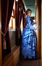 Young woman in blue vintage dress standing in corridor of retro Royalty Free Stock Photo