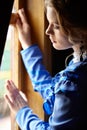 Young woman in blue vintage dress standing near window in coupe Royalty Free Stock Photo