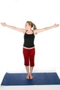 Young woman on blue yoga mat with arms out