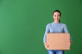 Young woman with box on color background. Moving into new house