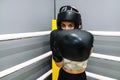 A young woman with boxing gloves and protective helmet throwing a punch to camera on a boxing ring