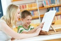 Young woman and boy reading book in library