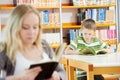 Young woman and boy reading book in library