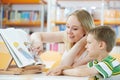 Young woman and boy reading book in library