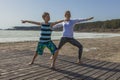Young woman and boy standing in yoga pose on the beach Royalty Free Stock Photo