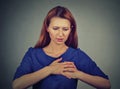 Young woman with breast pain touching chest isolated on gray wall background