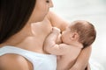 Young woman breastfeeding her baby on light background
