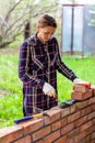 Young woman bricklayer lay out cement mortar for brickwork with a trowel on a brick wall. Royalty Free Stock Photo