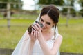 Young woman bride smiling and holding cute rabbit over park summer nature outdoor. White wedding dress, green background Royalty Free Stock Photo