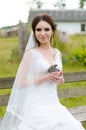 Young woman bride smiling and holding cute rabbit over park summer nature outdoor. White wedding dress, green background