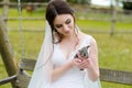 Young woman bride smiling and holding cute rabbit over park summer nature outdoor. White wedding dress, green background Royalty Free Stock Photo