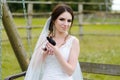 Young woman bride smiling and holding cute rabbit over park summer nature outdoor. White wedding dress, green background Royalty Free Stock Photo