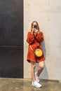 A young woman in a bright dress and sneakers with a phone in her hands. Using your smartphone