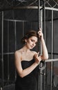 Young woman with bright evening makeup in a black dress posing near huge birdcage. An elegant lady with fashionable