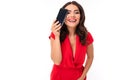 A young woman with bright makeup, in a red summer dress stands with a phone in hand and smiles Royalty Free Stock Photo