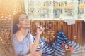 A young woman with bright makeup is sitting in a summer outdoor cafe in a hanging chair and blowing soap bubbles Royalty Free Stock Photo