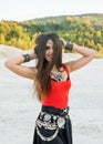 Young woman in a bright red top and ethnic jewelery laughing playfully holding in the wind flowing hair Royalty Free Stock Photo