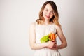 Young woman in a bright room holding a carrot Royalty Free Stock Photo