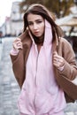 Young woman in brown coat and pink hoody posing on the street