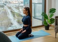 Young woman with brown hair in tracksuit sits in yoga pose