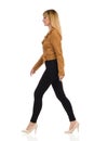 Young Woman In Brown Suede Jacket Is Walking And Looking Away. Side View Royalty Free Stock Photo