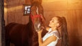 Young woman brunette with ponytail kisses horse with smile