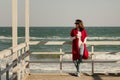 Young woman brunette in a red cardigan and light blue jeans wa