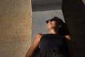 Young woman, brunette, slender, dressed in black and wearing sunglasses, lying on a bench receiving the sun's rays relaxed. Royalty Free Stock Photo